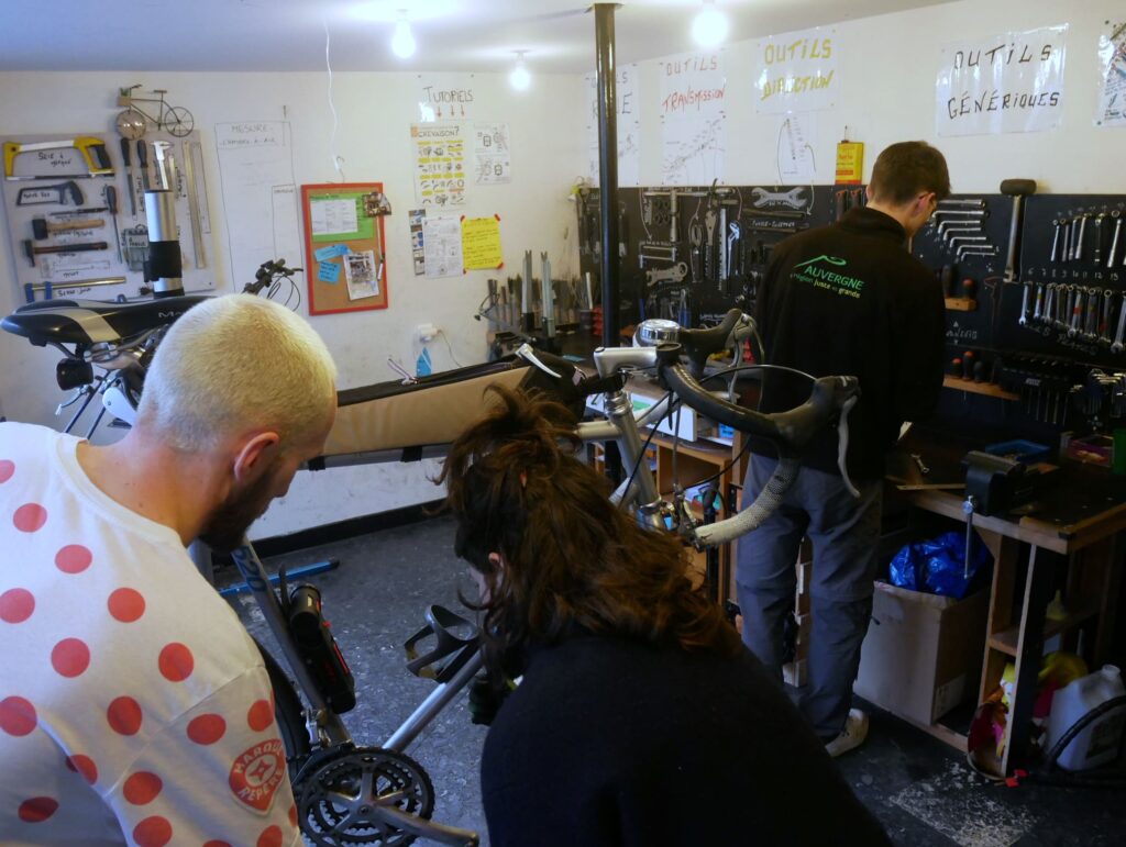Des bénévoles en train de réparer le vélo d'un adhérent dans l'atelier de l'association à clermont-ferrand